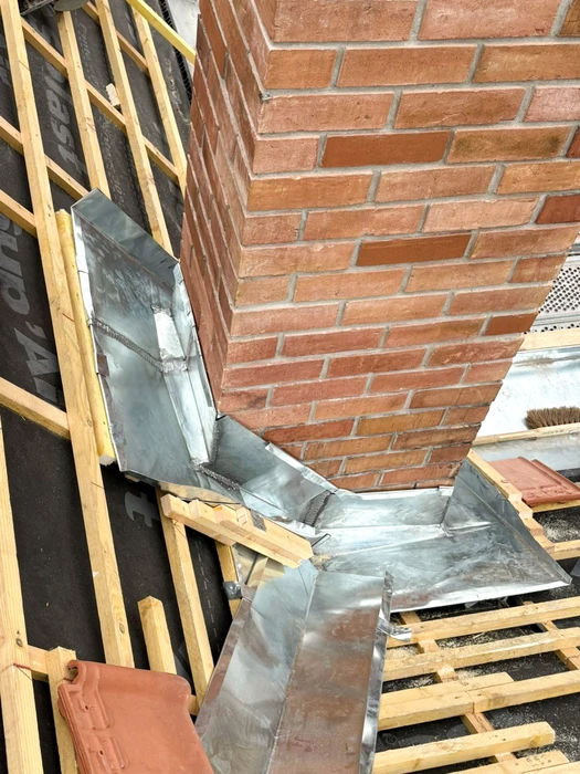 Chantier de toiture en cours, vue en plongée sur une cheminée en briques rouges
