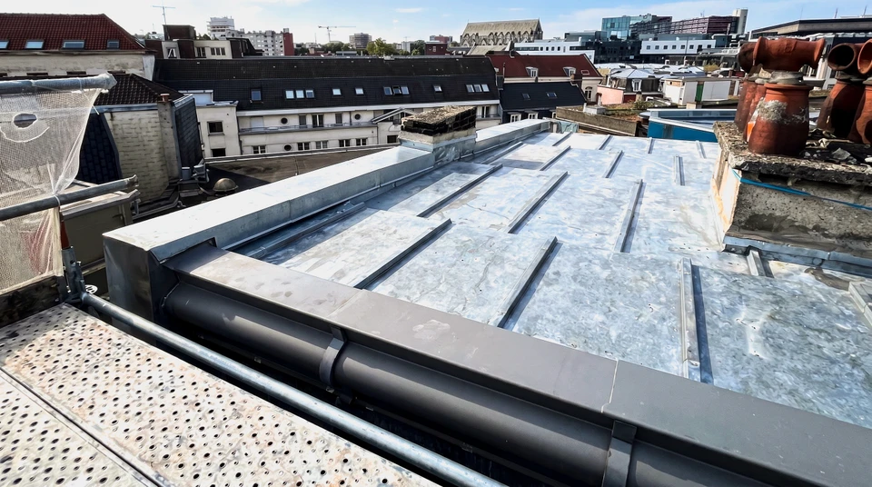 Chantier de construction résidentielle en extérieur, toiture en tuiles métalliques grises ondulées avec gouttière aluminium installée