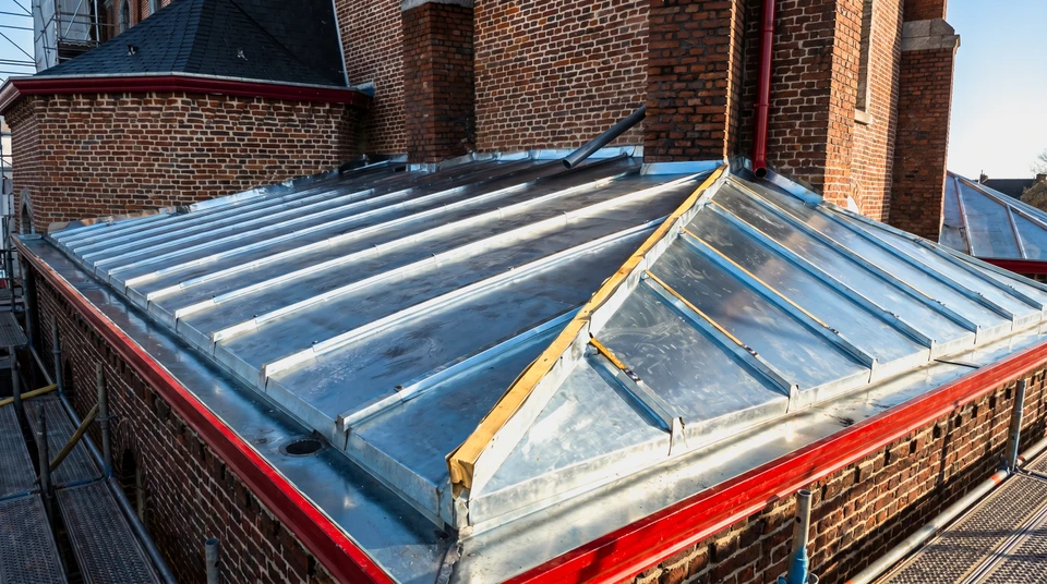 Extérieur, vue en contre-plongée d'une toiture pyramidale en ardoises avec charpente apparente et girouette décorative au sommet