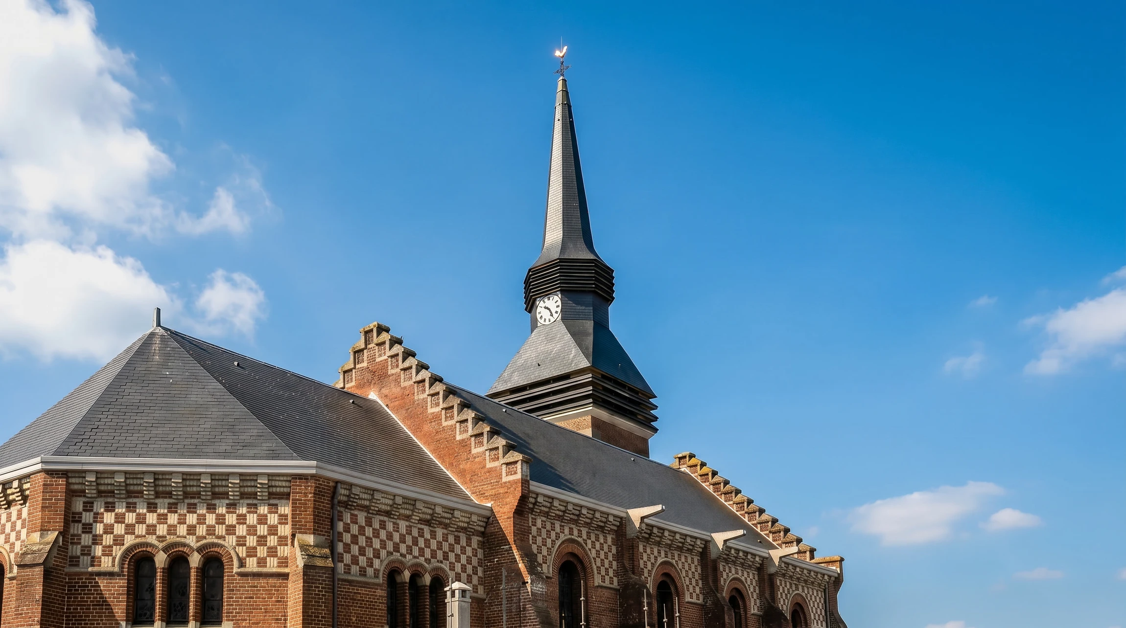 Vue aérienne d'une église en brique rouge avec toiture en ardoise naturelle bleue-grise récemment rénovée